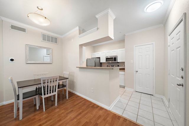 1330 Old Spanish Trl Unit 5203, Houston, TX 77054 - kitchen featuring appliances with stainless steel finishes, crown molding, white cabinetry, light wood finished floors, and baseboards