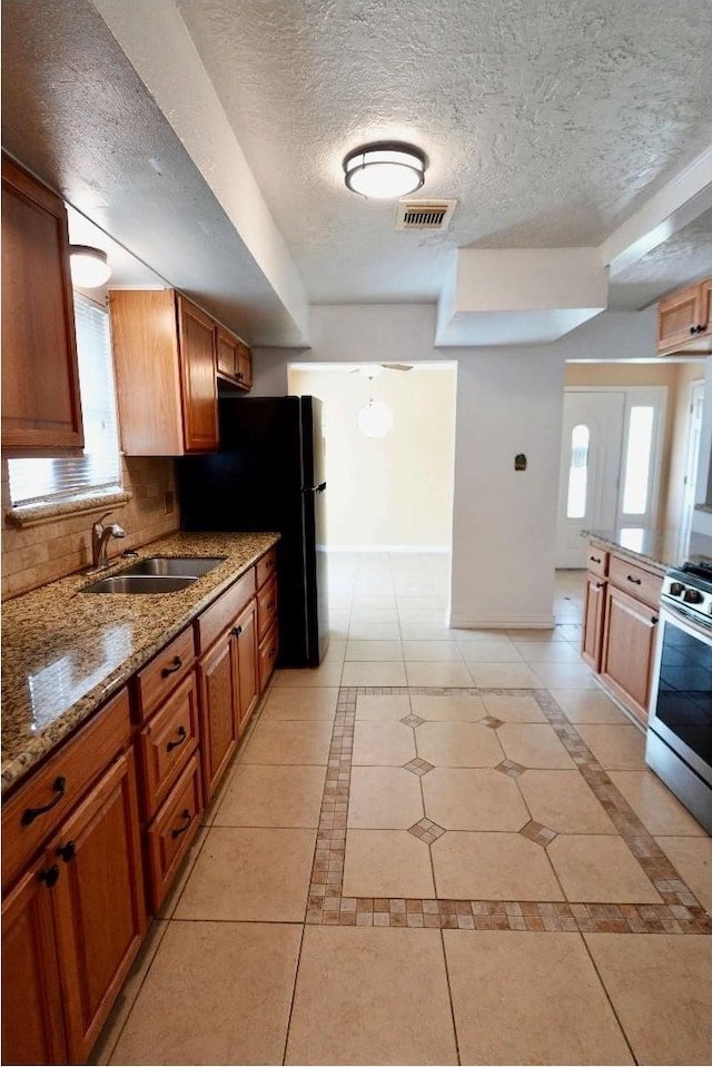 631 Soft Shadows Ln, Houston, TX 77013 - kitchen with stainless steel range, baseboards, a sink, stone countertops, and a textured ceiling