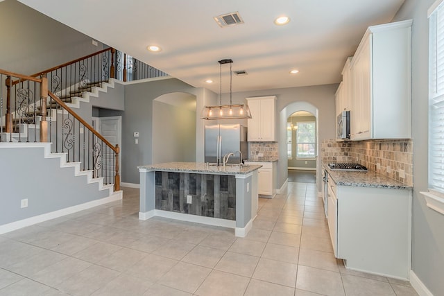 13516 Northline Lake Dr, Houston, TX 77044 - kitchen with arched walkways, stainless steel appliances, decorative backsplash, light stone counters, and white cabinetry
