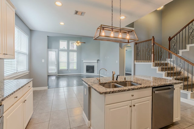 13516 Northline Lake Dr, Houston, TX 77044 - kitchen with a sink, stainless steel dishwasher, ceiling fan, an island with sink, and a glass covered fireplace