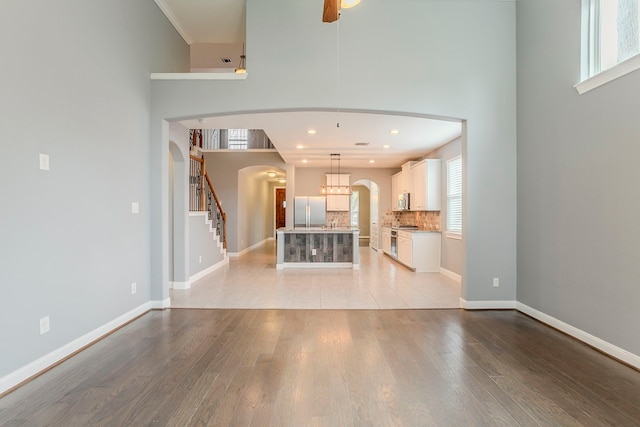 13516 Northline Lake Dr, Houston, TX 77044 - unfurnished living room with arched walkways, a high ceiling, light wood-style floors, healthy amount of natural light, and stairs