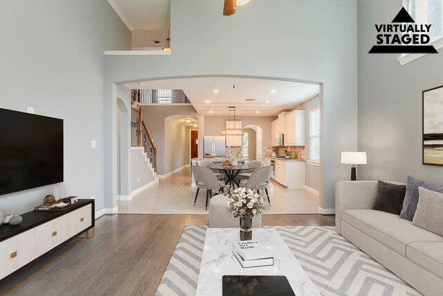 13516 Northline Lake Dr, Houston, TX 77044 - living room featuring arched walkways, a high ceiling, stairway, light wood-style flooring, and baseboards