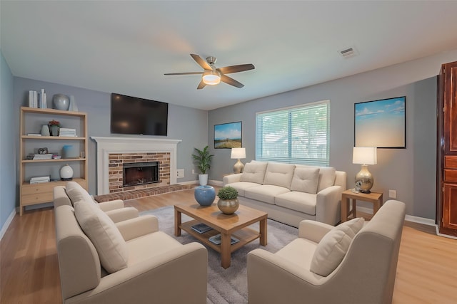 1010 Cheyenne Meadows Dr, Katy, TX 77450 - living room featuring ceiling fan, light wood-style flooring, baseboards, and a fireplace