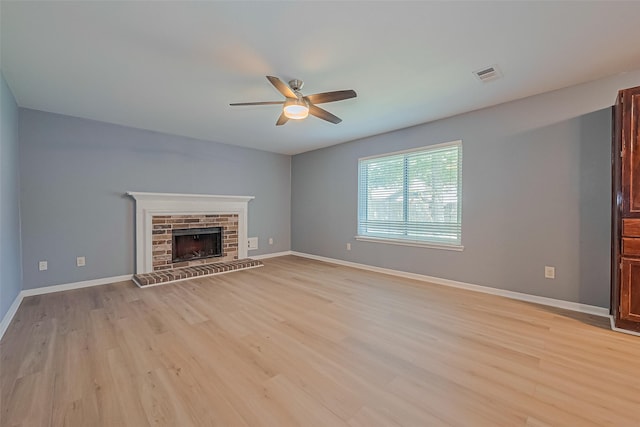 1010 Cheyenne Meadows Dr, Katy, TX 77450 - unfurnished living room featuring a ceiling fan, light wood-style flooring, a fireplace with raised hearth, and baseboards