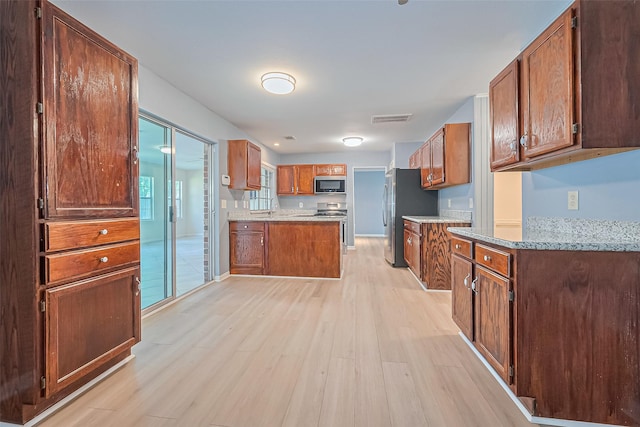 1010 Cheyenne Meadows Dr, Katy, TX 77450 - kitchen featuring stainless steel appliances, light wood-type flooring, a sink, and brown cabinetry