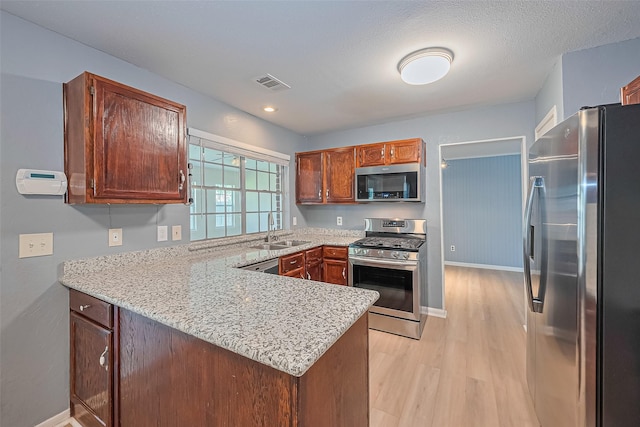 1010 Cheyenne Meadows Dr, Katy, TX 77450 - kitchen featuring stainless steel appliances, a sink, a peninsula, light wood-style flooring, and baseboards