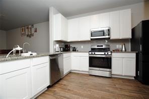 4619 Ehrlich Ct, Rosenberg, TX 77471 - kitchen featuring stainless steel appliances, white cabinets, a sink, a peninsula, and dark wood-style flooring