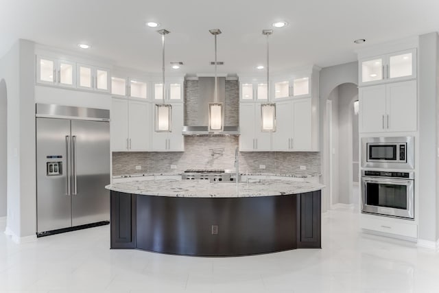 3650 Sage Hollow Dr, Spring, TX 77386 - kitchen featuring built in appliances, wall chimney exhaust hood, arched walkways, decorative backsplash, and recessed lighting