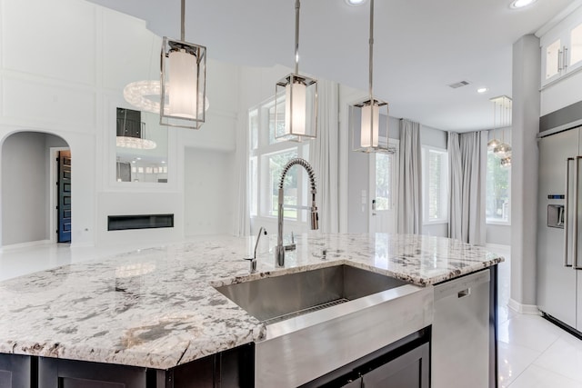 3650 Sage Hollow Dr, Spring, TX 77386 - kitchen featuring a sink, appliances with stainless steel finishes, arched walkways, pendant lighting, and light stone countertops