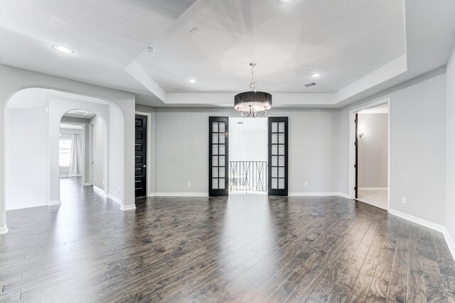 3650 Sage Hollow Dr, Spring, TX 77386 - unfurnished living room featuring a tray ceiling, arched walkways, wood finished floors, a chandelier, and recessed lighting
