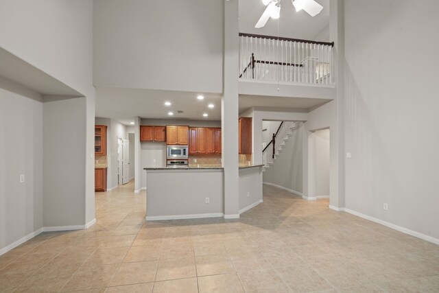 17426 Memorial Blossom Dr, Spring, TX 77379 - kitchen with stainless steel appliances, a high ceiling, brown cabinets, light tile patterned floors, and ceiling fan