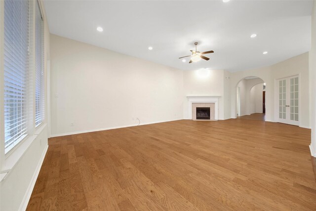 10938 Glenrothers Dr, Richmond, TX 77407 - unfurnished living room featuring arched walkways, ceiling fan, light wood-style flooring, a tiled fireplace, and recessed lighting