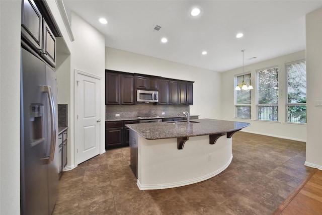 10938 Glenrothers Dr, Richmond, TX 77407 - kitchen featuring appliances with stainless steel finishes, a kitchen bar, dark brown cabinets, a chandelier, and dark stone counters