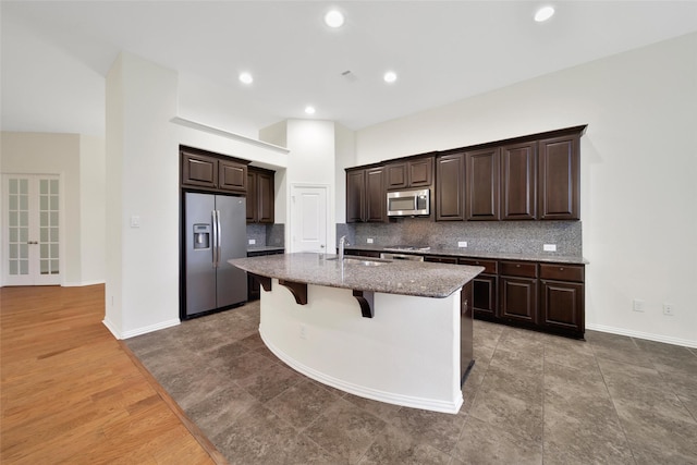 10938 Glenrothers Dr, Richmond, TX 77407 - kitchen featuring stainless steel appliances, a kitchen island with sink, backsplash, a kitchen breakfast bar, and dark brown cabinetry