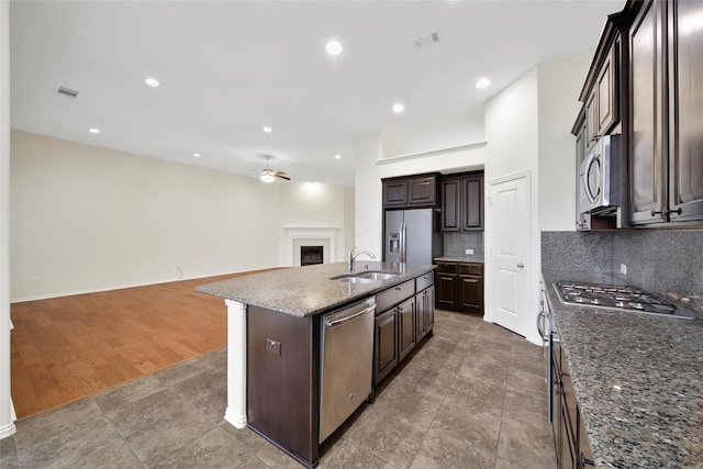10938 Glenrothers Dr, Richmond, TX 77407 - kitchen featuring appliances with stainless steel finishes, a ceiling fan, tasteful backsplash, open floor plan, and a kitchen island with sink