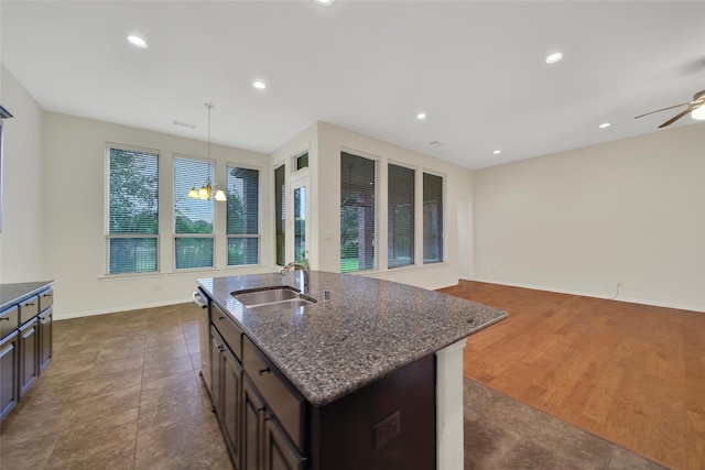 10938 Glenrothers Dr, Richmond, TX 77407 - kitchen featuring dark stone counters, ceiling fan, recessed lighting, a center island with sink, and dark brown cabinets