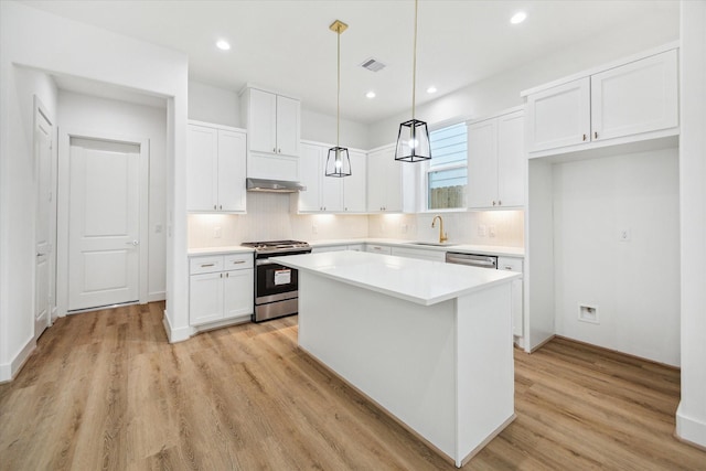 1212 Nadine St, Houston, TX 77009 - kitchen with stainless steel gas stove, a sink, under cabinet range hood, a center island, and white cabinetry