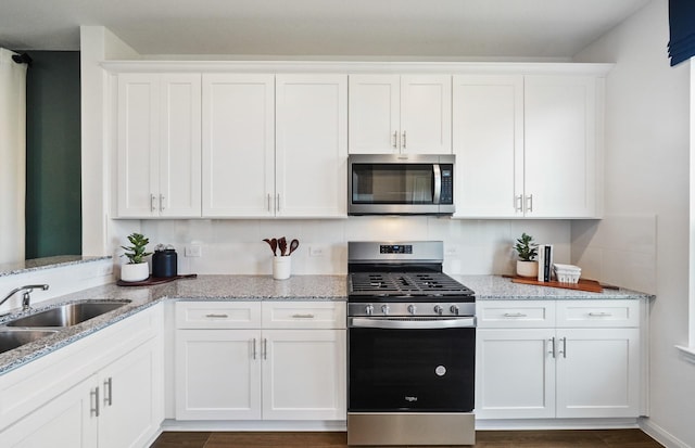 25319 Merino Dr, Magnolia, TX 77355 - kitchen with stainless steel appliances, white cabinetry, light stone counters, and a sink