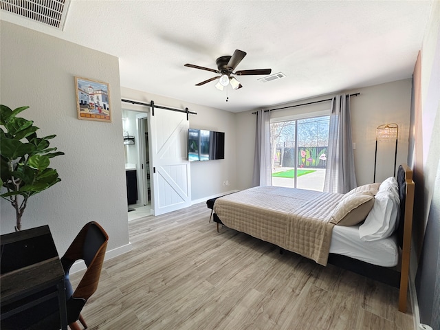 11810 Sagedowne Ln, Houston, TX 77089 - bedroom with a barn door, access to exterior, light wood-style floors, and baseboards