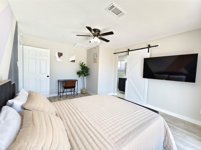 11810 Sagedowne Ln, Houston, TX 77089 - bedroom featuring a barn door, light wood-style flooring, baseboards, and ceiling fan