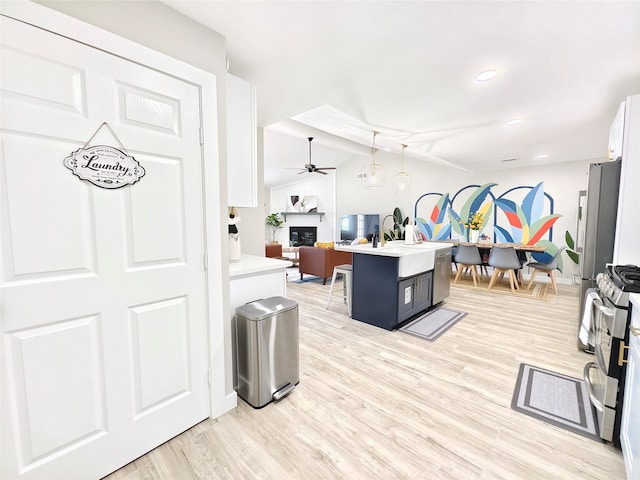 11810 Sagedowne Ln, Houston, TX 77089 - kitchen featuring a ceiling fan, a fireplace, open floor plan, appliances with stainless steel finishes, and light wood-style floors