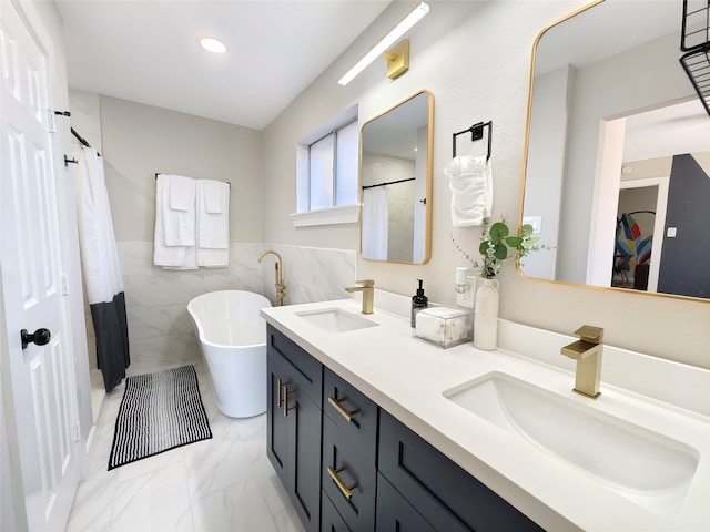 11810 Sagedowne Ln, Houston, TX 77089 - full bath featuring double vanity, a freestanding bath, marble look tile flooring, tile walls, and a wainscoted wall