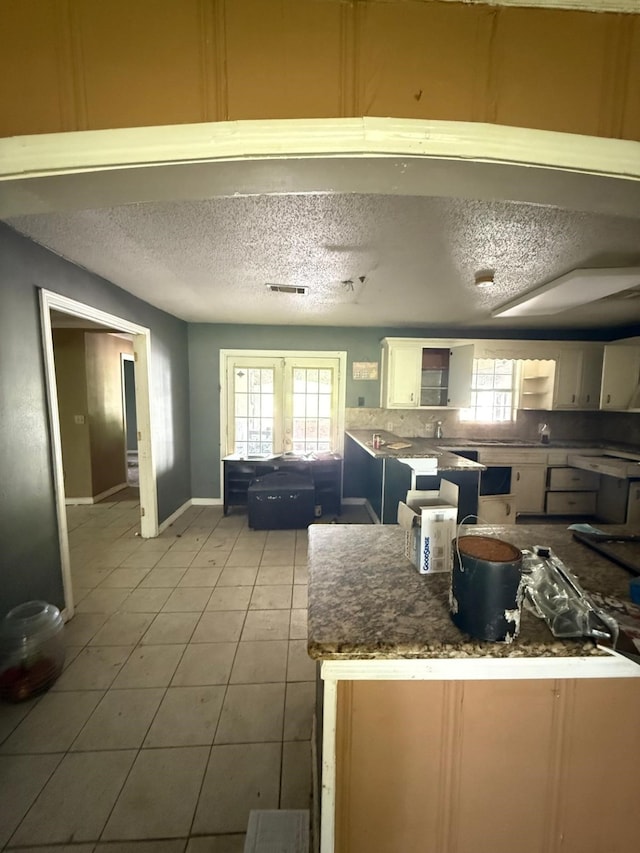 15125 S Dr, Channelview, TX 77530 - kitchen featuring a textured ceiling, light tile patterned floors, white cabinets, and baseboards