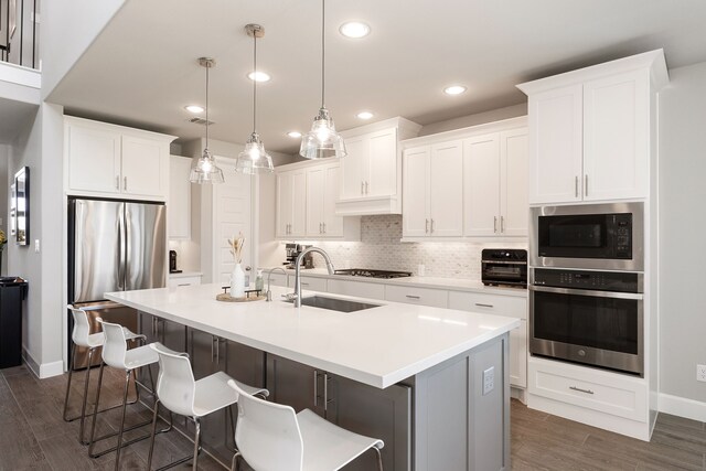 1918 Longcroft Ln, Katy, TX 77493 - kitchen featuring appliances with stainless steel finishes, a sink, dark wood-style flooring, a breakfast bar area, and a kitchen island with sink