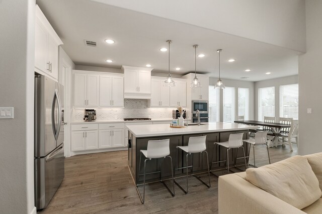 1918 Longcroft Ln, Katy, TX 77493 - kitchen featuring stainless steel appliances, a breakfast bar, decorative backsplash, white cabinets, and recessed lighting