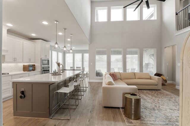1918 Longcroft Ln, Katy, TX 77493 - kitchen with white cabinetry, a large island, light wood-type flooring, light countertops, and a high ceiling