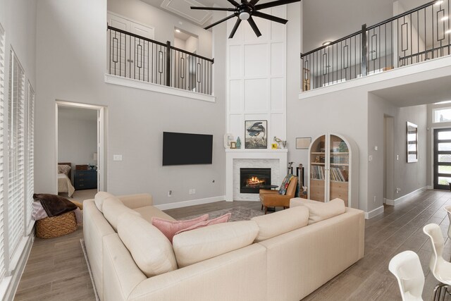 1918 Longcroft Ln, Katy, TX 77493 - living room featuring a high ceiling, ceiling fan, a large fireplace, wood finished floors, and baseboards