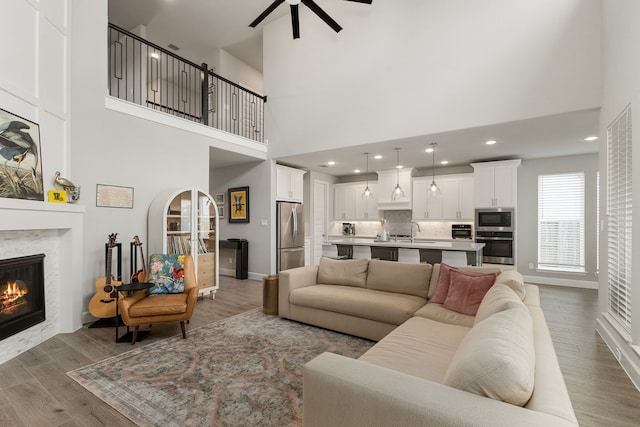 1918 Longcroft Ln, Katy, TX 77493 - living room with ceiling fan, light wood finished floors, a tile fireplace, a towering ceiling, and recessed lighting