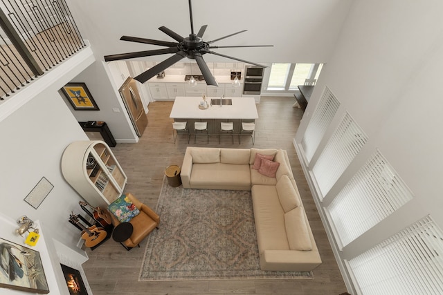 1918 Longcroft Ln, Katy, TX 77493 - living area featuring a high ceiling, ceiling fan, wood finished floors, a warm lit fireplace, and baseboards