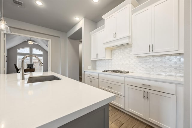 10522 Rigel Ridge Way, Richmond, TX 77406 - kitchen featuring a sink, stainless steel gas stovetop, ceiling fan, light countertops, and decorative backsplash