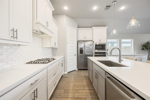 10522 Rigel Ridge Way, Richmond, TX 77406 - kitchen with appliances with stainless steel finishes, a sink, light wood finished floors, light countertops, and tasteful backsplash