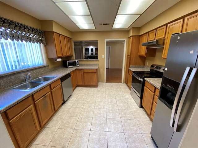 3306 High Pine Dr, Missouri City, TX 77459 - kitchen with stainless steel appliances, a sink, brown cabinetry, and under cabinet range hood