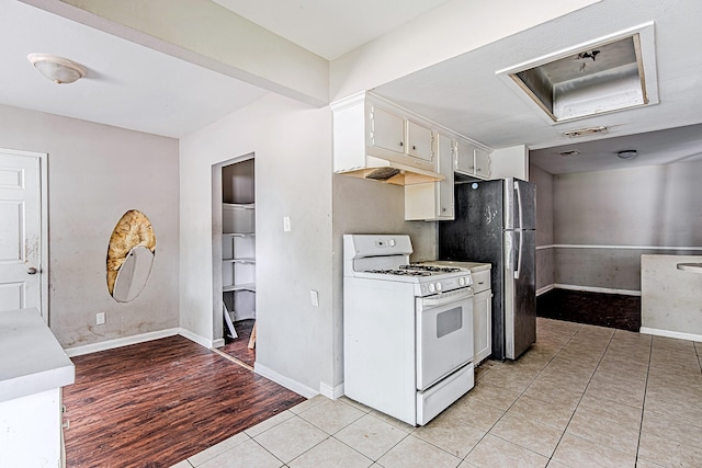 1006 Fruitvale Dr, Houston, TX 77038 - kitchen with white gas range, freestanding refrigerator, light countertops, light wood finished floors, and white cabinets
