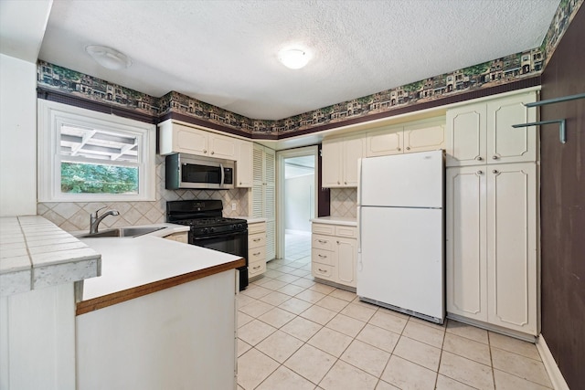 7658 El Rancho St, Houston, TX 77087 - kitchen with freestanding refrigerator, stainless steel microwave, gas stove, a sink, and a textured ceiling