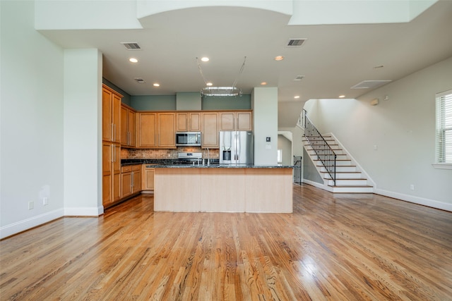 2915 Pease St, Houston, TX 77003 - kitchen featuring stainless steel appliances, light wood-style flooring, tasteful backsplash, a center island with sink, and recessed lighting