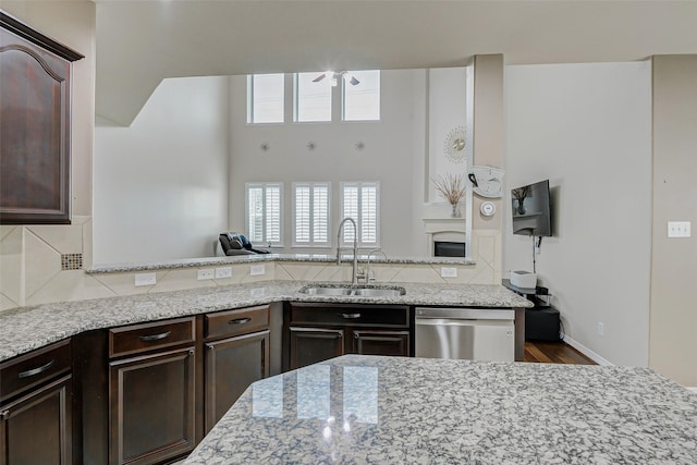 4114 Elk Bluff Ln, Katy, TX 77494 - kitchen featuring dishwasher, a sink, dark brown cabinets, and light stone countertops