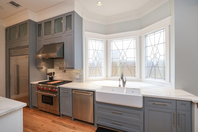 1132 Oxford St, Houston, TX 77008 - kitchen with under cabinet range hood, gray cabinets, premium appliances, a sink, and light stone counters