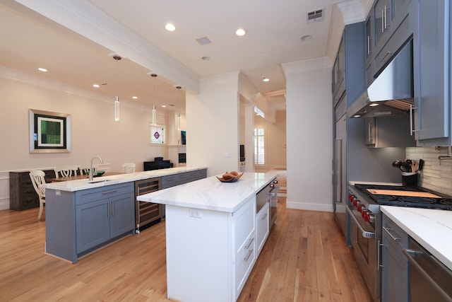 1132 Oxford St, Houston, TX 77008 - kitchen featuring wine cooler, crown molding, a sink, a kitchen island, and light stone counters