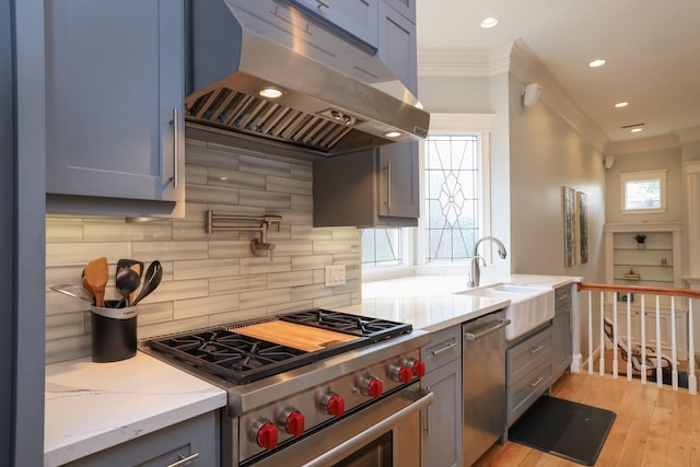 1132 Oxford St, Houston, TX 77008 - kitchen featuring under cabinet range hood, stainless steel appliances, a sink, ornamental molding, and light stone counters