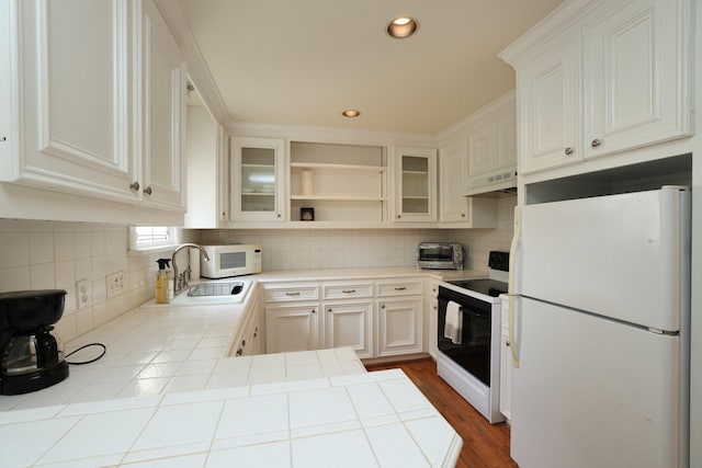 1132 Oxford St, Houston, TX 77008 - kitchen featuring white appliances, under cabinet range hood, a sink, tile counters, and backsplash
