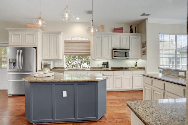 3807 Snead Ct, Sugar Land, TX 77479 - kitchen featuring stainless steel appliances, a sink, a center island, light wood-style floors, and light stone counters