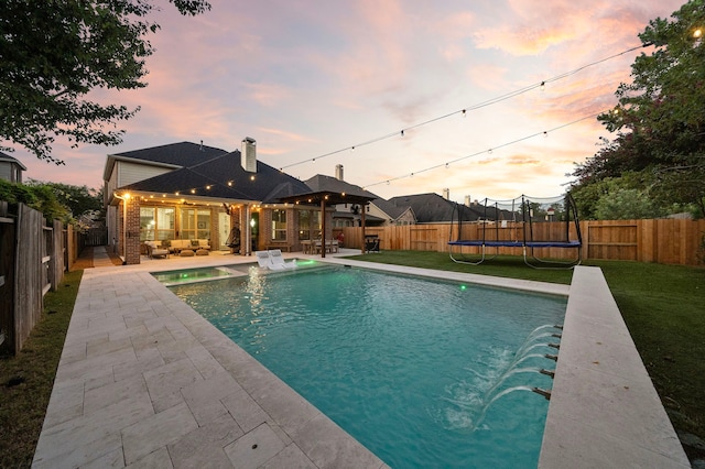 8442 Horsepen Bend Dr, Conroe, TX 77385 - pool at dusk featuring a trampoline, a patio, and an outdoor living space