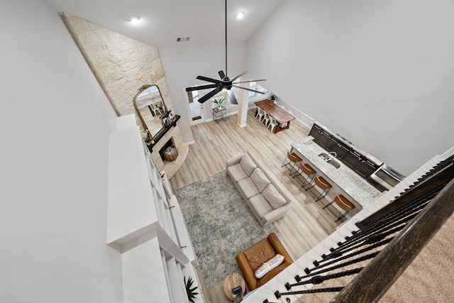 8442 Horsepen Bend Dr, Conroe, TX 77385 - living area with a stone fireplace, wood finished floors, high vaulted ceiling, a ceiling fan, and baseboards