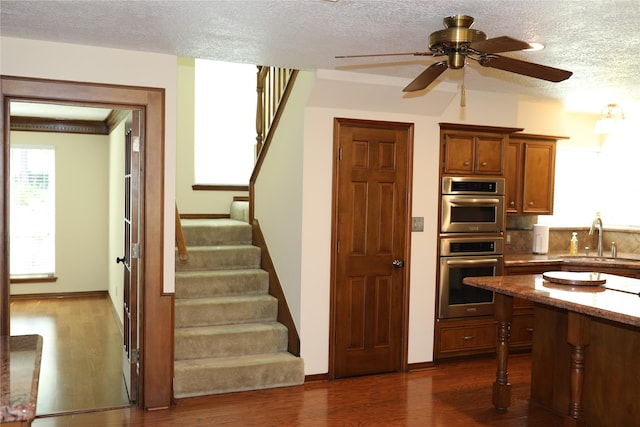 3003 Roseheath Ln, Houston, TX 77073 - kitchen featuring a sink, brown cabinetry, dark wood-style flooring, a ceiling fan, and a textured ceiling