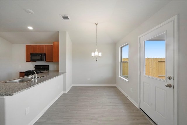 805 Clear Valley Ln, Dayton, TX 77535 - kitchen featuring black appliances, a sink, brown cabinets, light wood-style floors, and a chandelier
