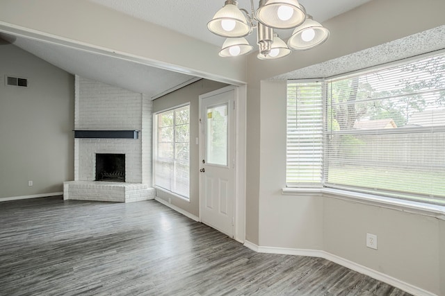 5606 Cypressgate Dr, Spring, TX 77373 - unfurnished living room featuring a chandelier, wood finished floors, vaulted ceiling, a brick fireplace, and baseboards